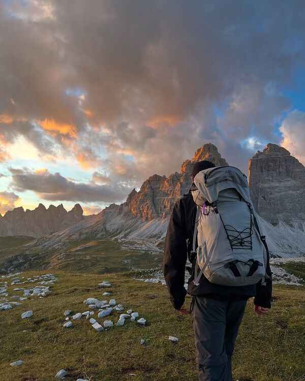 Adult walker standing near a mountain trail with a backpack